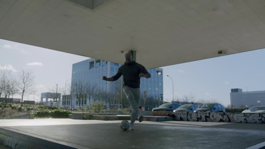 Man in an open lobby doing freestyle with the soccer ball
