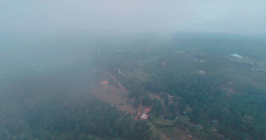 Aerial panorama of houses amid hills and forests on a foggy day