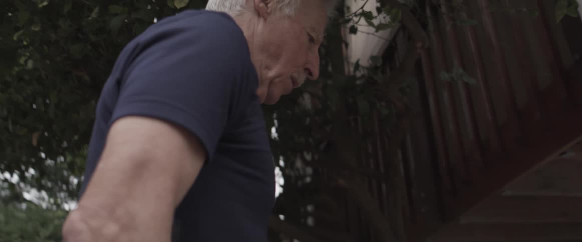 Elderly man walking on makeshift shoes in the backyard