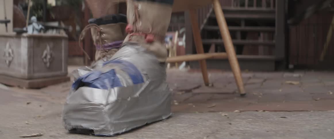 Elderly man testting makeshift shoes in the backyard