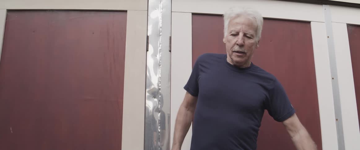 White haired man steps sideways slowly while wearing big bulky footwear