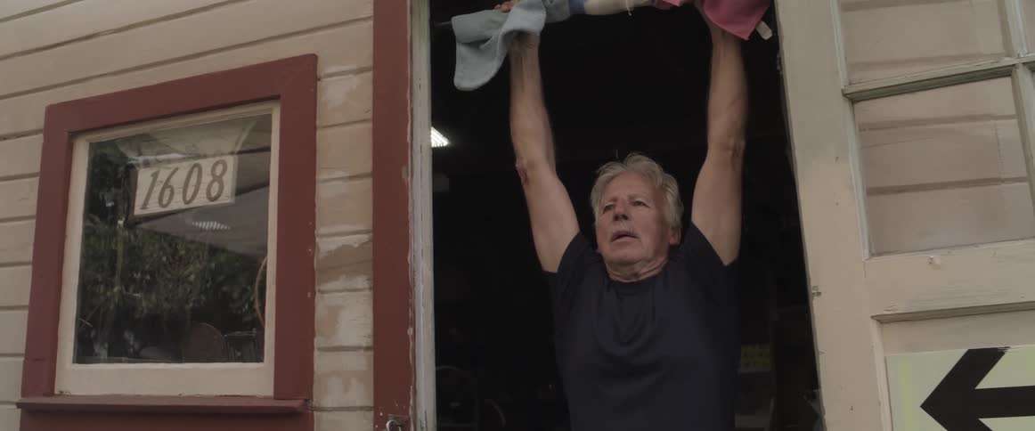 Elderly man doing pull ups in the door frame of his home