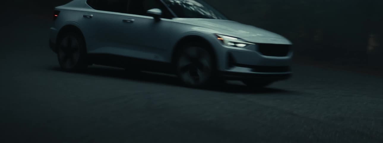 A silver car driving on an asphalt street at night