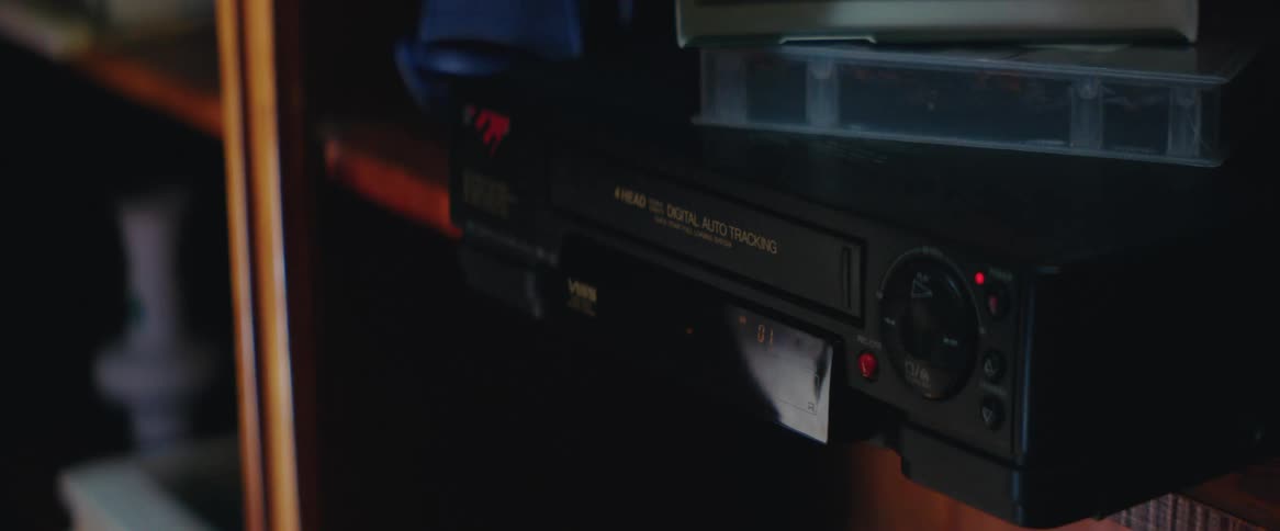 A pair of hands inserting a cassette into a vcr