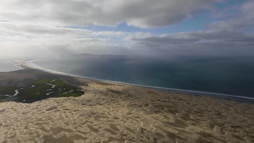 Aerial panorama of a peninsula with yellowish and greenish soil on the edge of a vast sea
