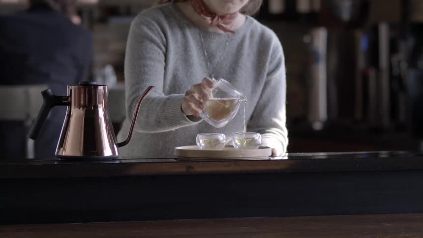 A woman pours and has a drink