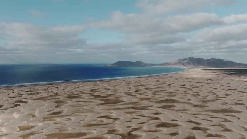 Aerial panorama of an island with a peninsula with a sea and sand on a blue sky day with clouds