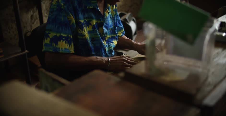 A man is sitting at a table spreading rolling paper out