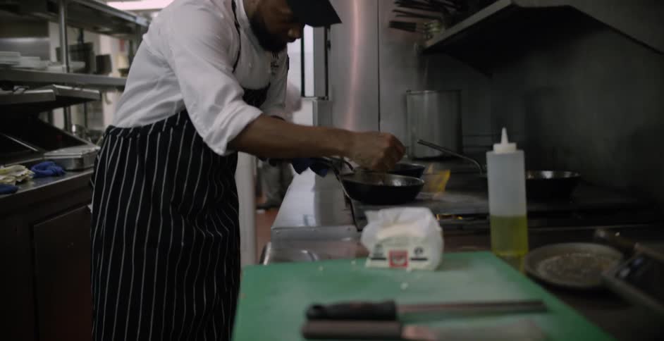A chef is stirring food in a pan on the fire
