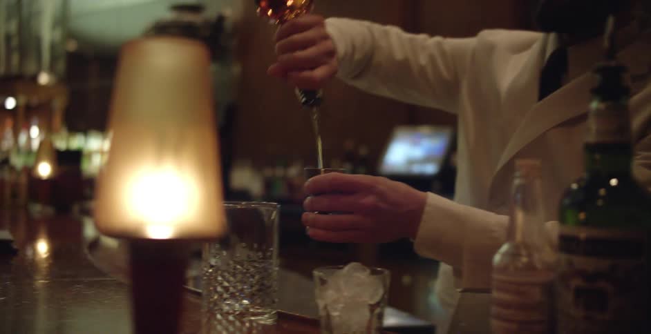 Sharp dressed man pouring liquor into a shot glass