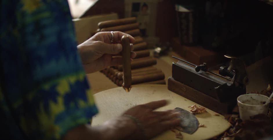 A man is rolling cigars at a table