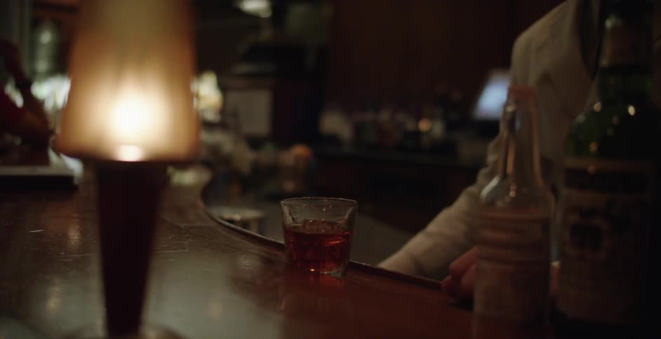 A bartender pours a mixed drink into a glass at a bar