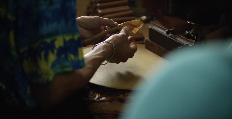 A woman cuts a cigar she is making