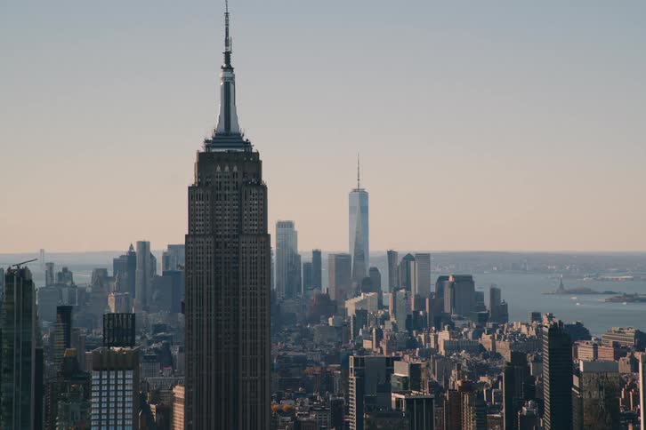 The aerial view depicts a skyscraper with a spire towering over the cityscape