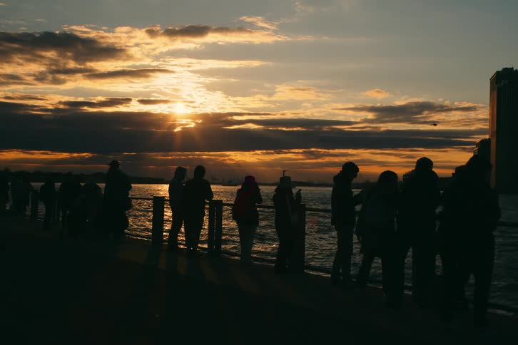 Silhouette of people in a handrail overlooking the sea in the late afternoon in a metropolis