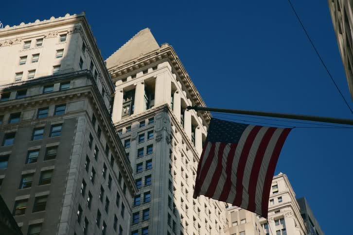 An american flag flying in a dense city