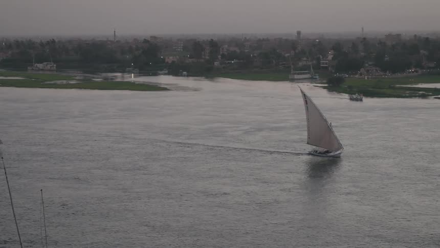Skyline of a sailing boat sailing in the sea near a city