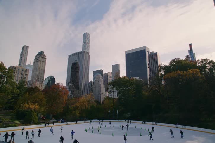 People skating on an ice rink in a big city park