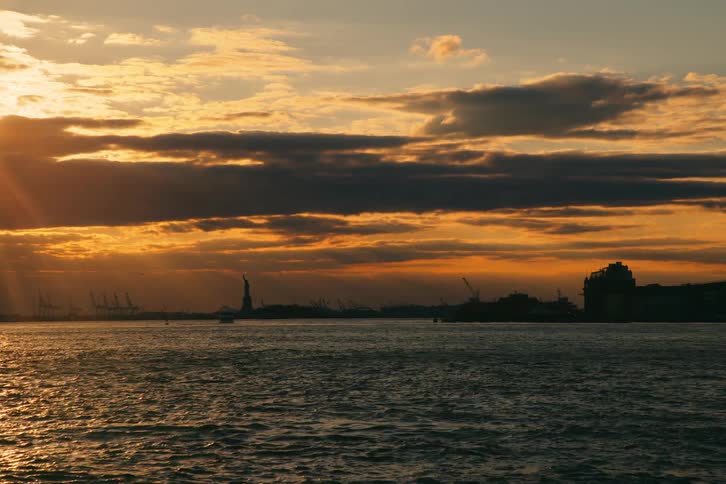 A boat sailing the waters of upper new york bay at sunset