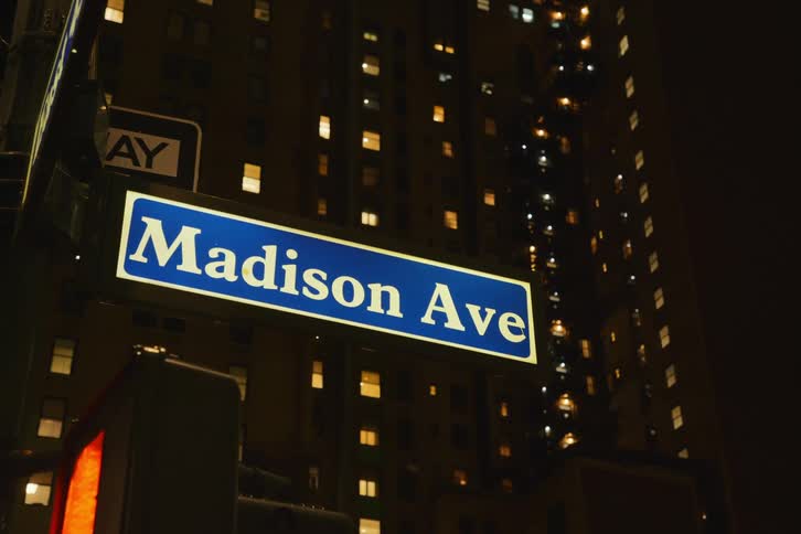 A street sign on a new york city corner showing madison avenue