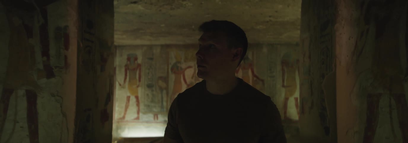 Man walking in a cave with drawings on the walls