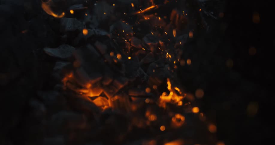 Burning coal ember rising in slow motion at night