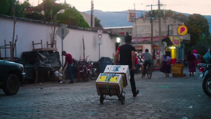 A worker hauls boxes down a city street