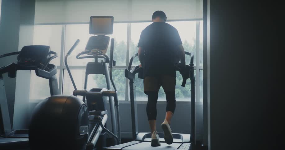 A frail man walks on a treadmill