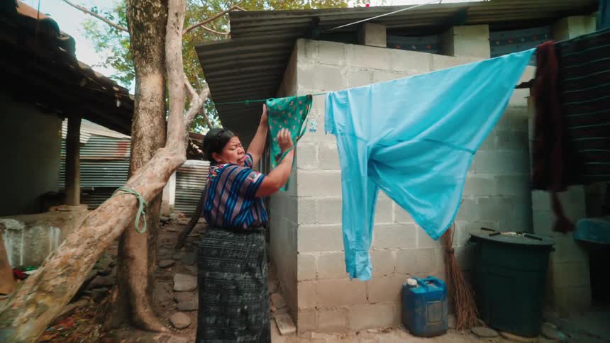 Woman outside her house hanging clothes on the clothesline