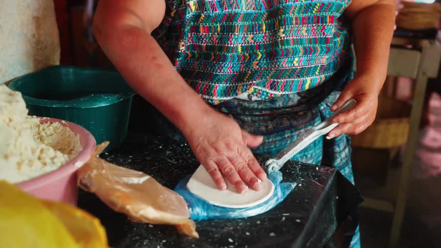 Woman flattened a flour mix with a tool and dressed it with her palms