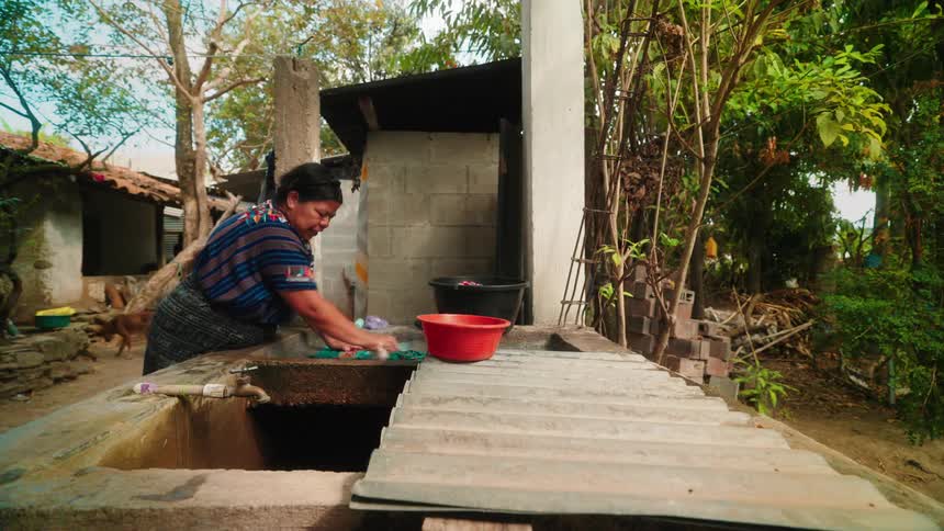 Woman in the backyard washing clothes with her hands