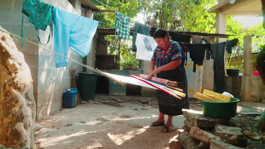 Woman in the backyard unwinding fabric on a rope