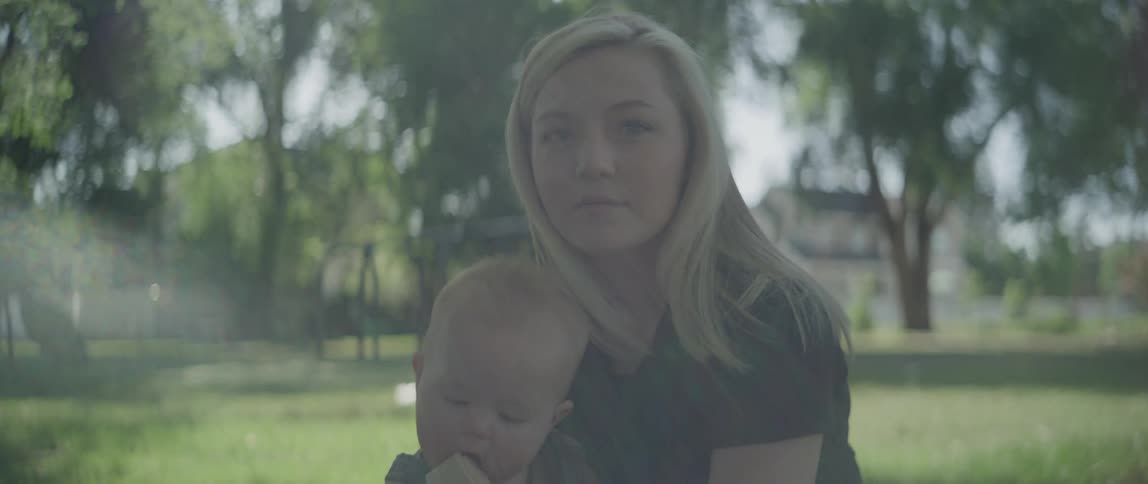 Portrait of mother sitting in a garden with her baby son on her lap