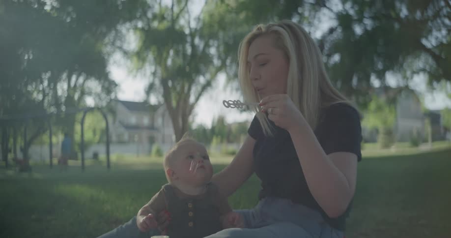 Mother and son in a park blowing soap bubbles outdoors