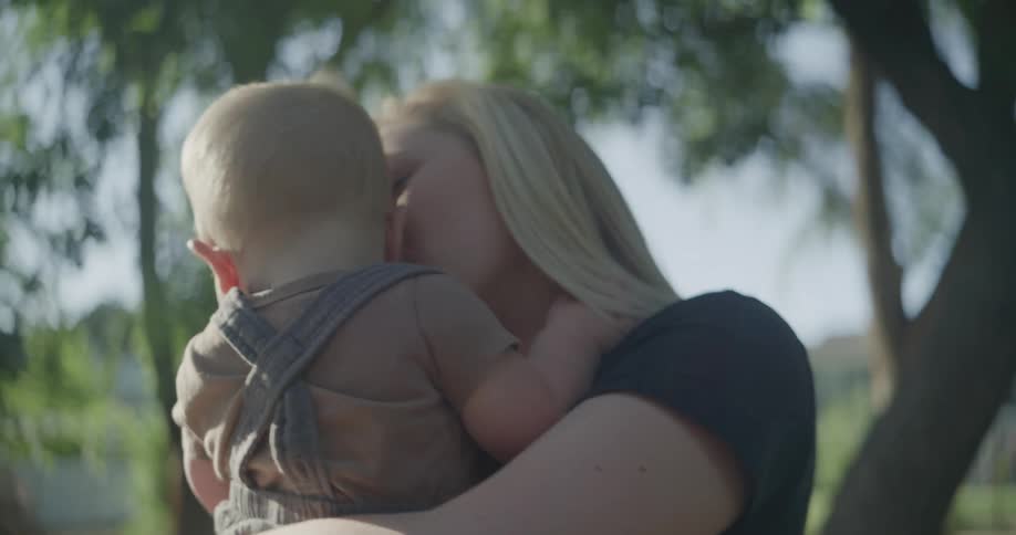 A mother holds and kisses her infant son