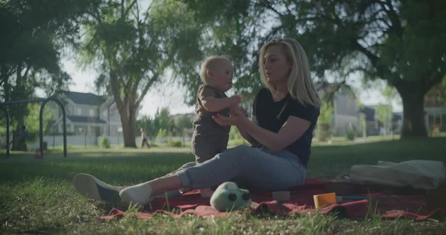 Mother sitting on a rug in the grass together with her baby
