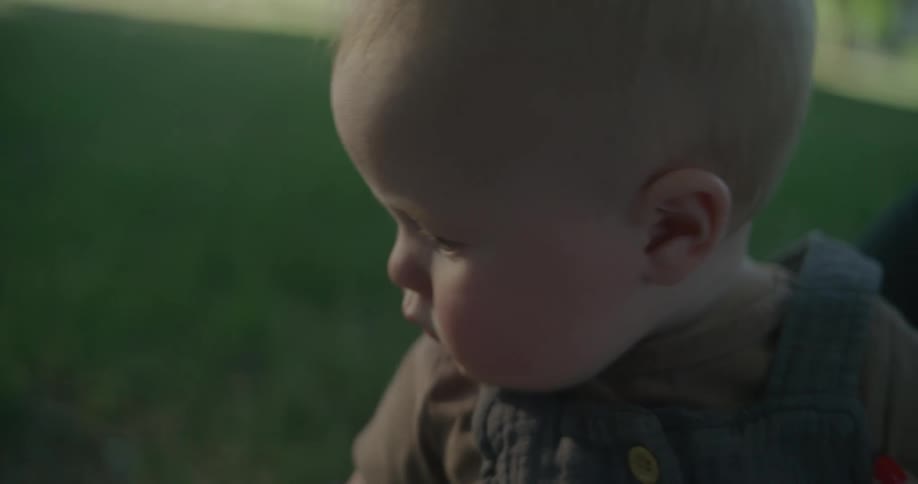 A baby sitting on the grass outdoor during the day