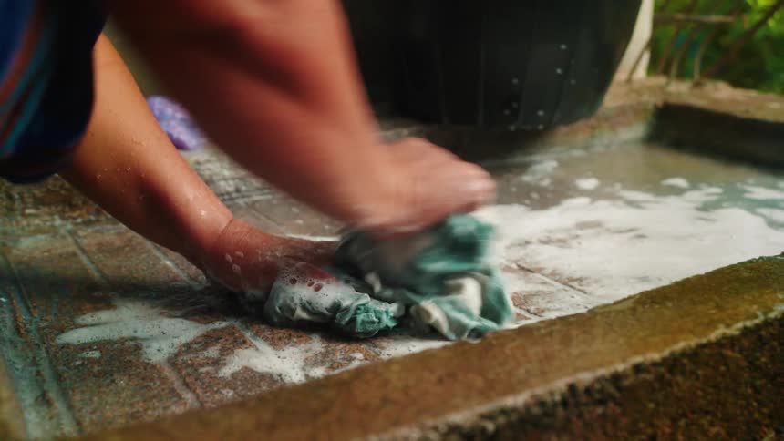 Close on the hands of a woman manually washing clothes in the sink