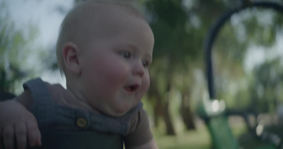 A happy baby on a swing in the park