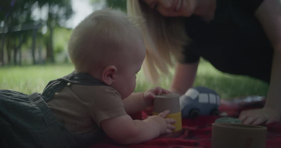 A mother is playing with her baby in the park