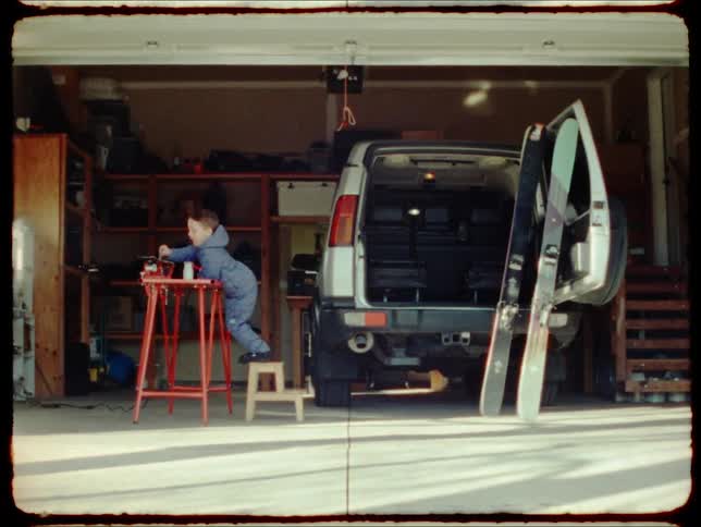 A child plays next to an suvs parked in a garage at home