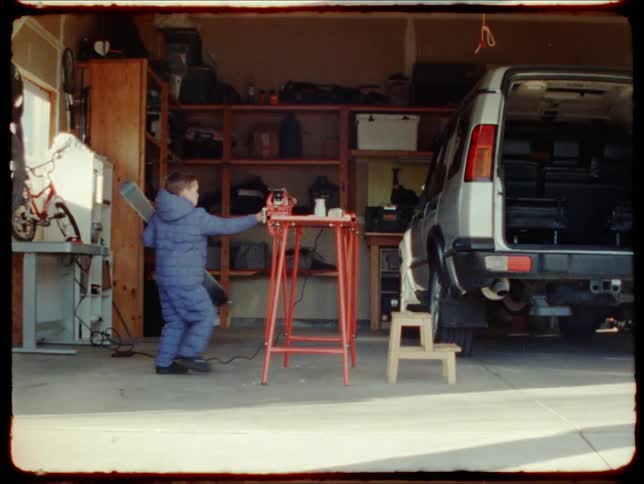 Little boy in the garage at home picking up equipment says he