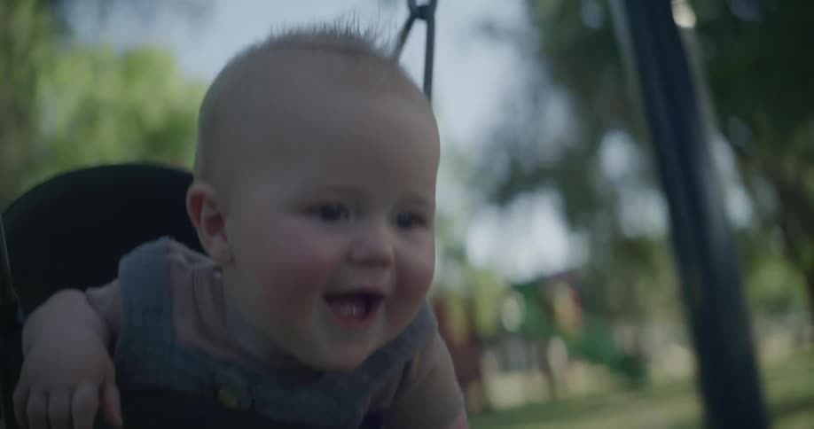 Portrait of a smiling baby while playing on a swing and outdoors