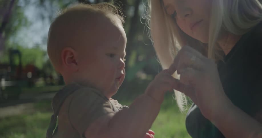 Mother sitting in a garden with her son drinking on her lap
