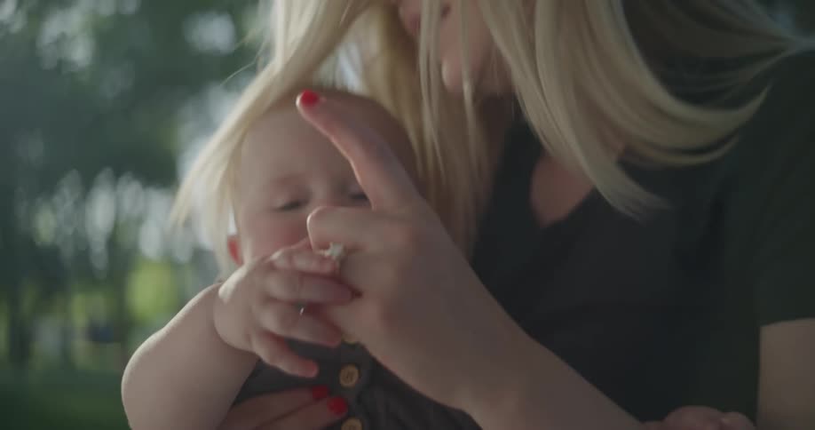 Mother and baby playing with their hands while sitting outdoor during the day