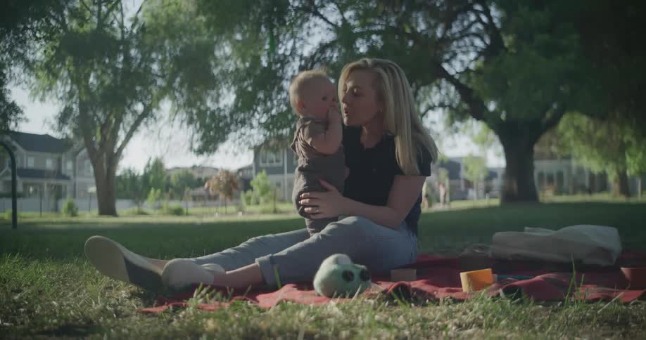 Mother sitting in a garden and holding her baby affectionately