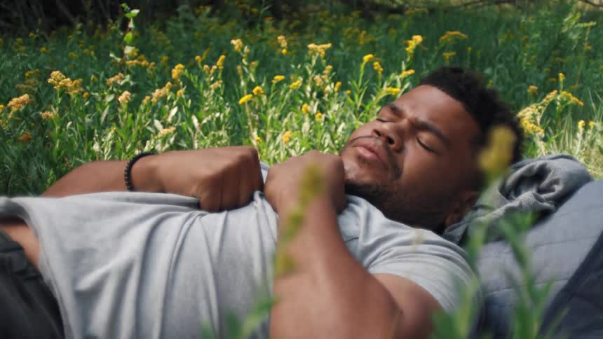 Man sleeps while lying on his back in a field of wildflowers