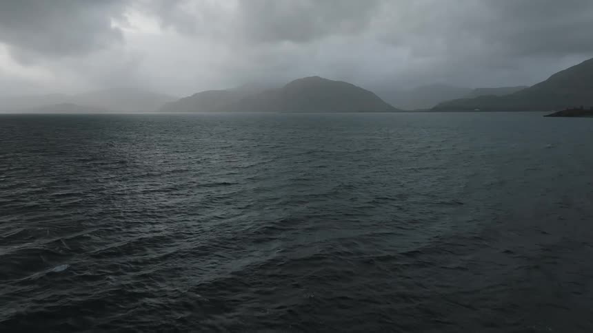 Panorama of the dark sea with mountains around on a cloudy day