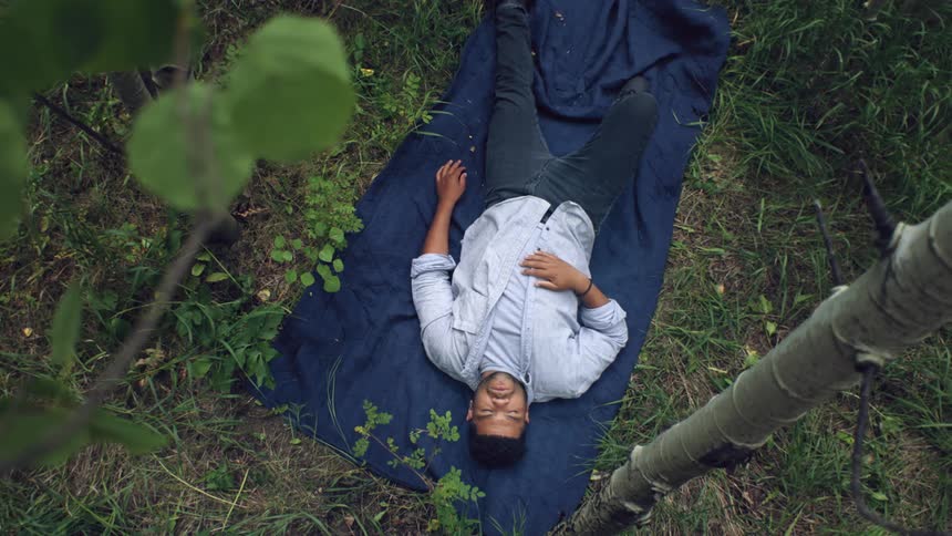 Man lying on a rug in the grass of a forest