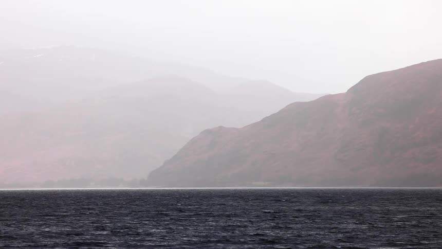 Sea landscape in slow motion with mountains around on a fog day
